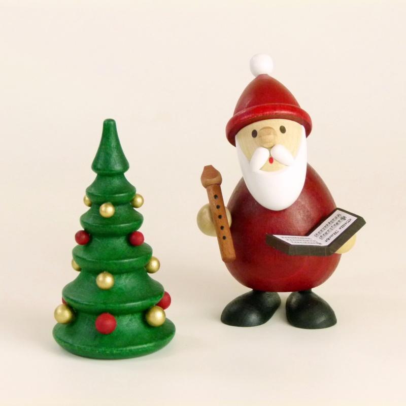 Holzfigur Weihnachtsmann mit Notenbuch und Flöte neben geschmücktem Tannenbaum, rot-weiß bemalt, von