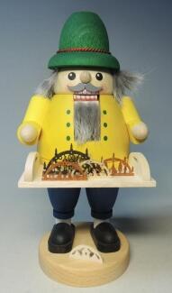Nussknacker – detailreicher Schwibbogenverkäufer mit grimmiger Miene, grüner Mütze und gelber Jacke 