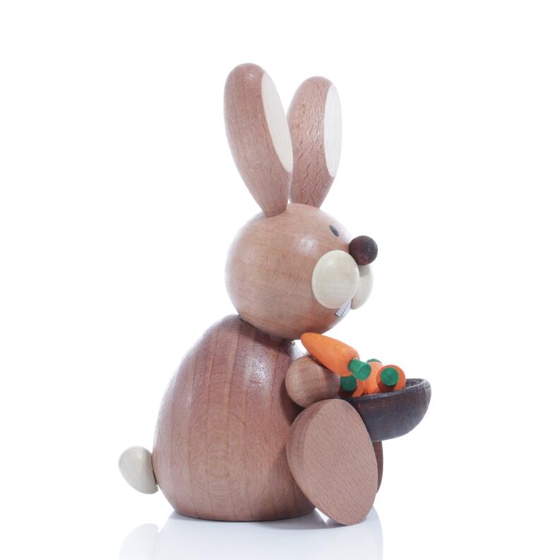 Seitliche Ansicht rechts des sitzenden Osterhasen mit Möhrenschüssel und Möhre im Mund aus Holz von
