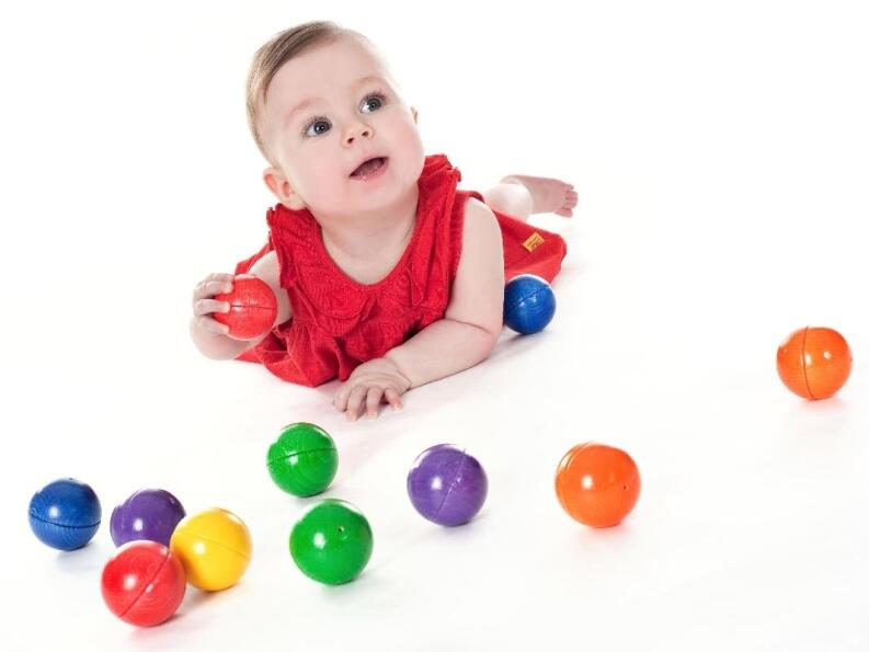 Holzspielzeug bunte klingende Holzkugeln von SINA Spielzeug GmbH, Baby spielt mit farbenfrohen