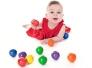 Baby in rotem Kleid spielt mit bunten Kugeln, hält eine rote Kugel in der Hand, weitere farbige